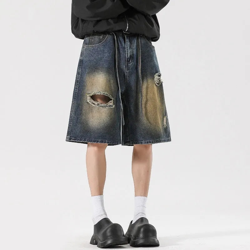 Man wearing loose fit retro blue ripped jeans with distressed details on knees and thighs