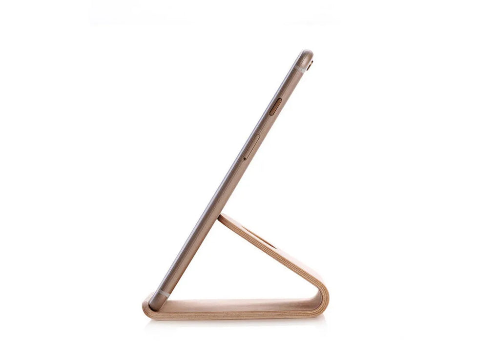 Solid walnut wooden stand holding an iPhone with charging cable routed through integrated channel