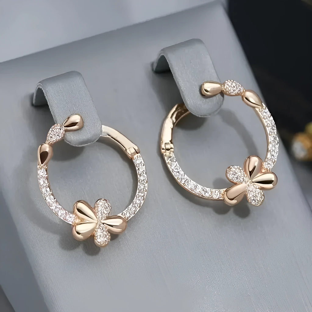 A pair of round gold-coloured hoop earrings with a geometric ring design on a plain background.