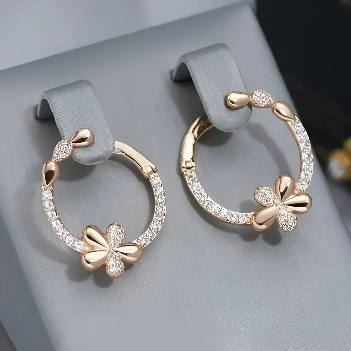 A pair of round gold-coloured hoop earrings with a geometric ring design on a plain background.