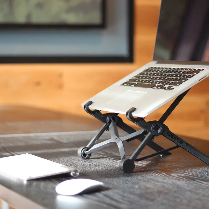 Black folding portable laptop stand made of reinforced nylon, shown in folded position.