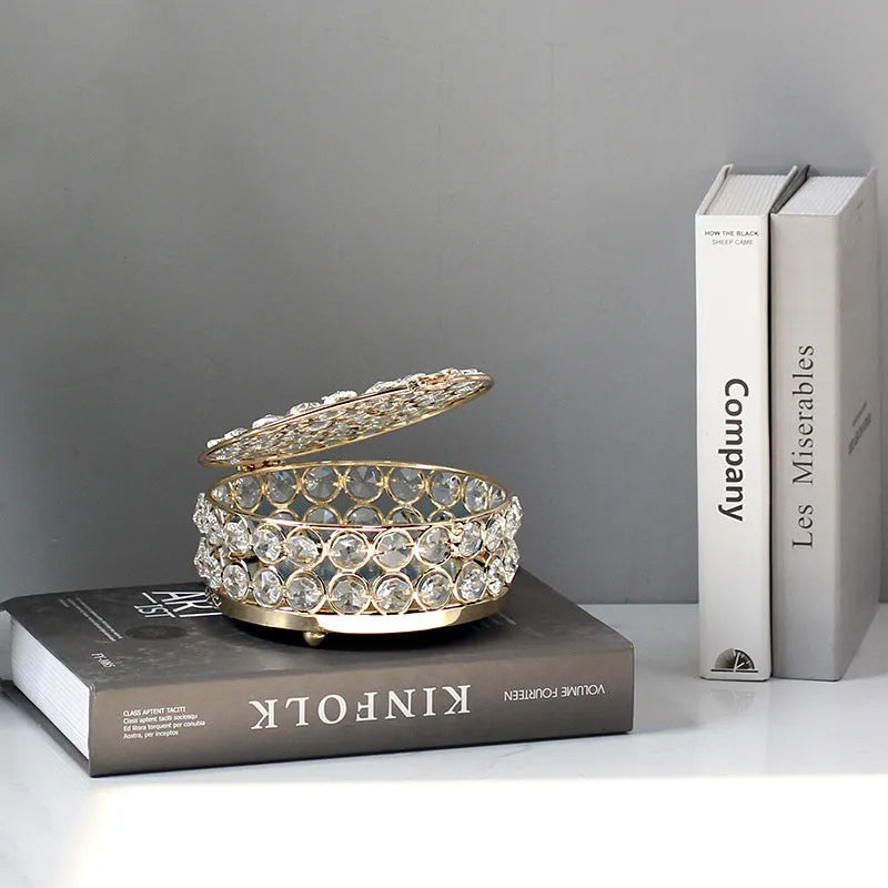 Transparent crystal glass jewelry storage box with ornate French gold metal frame.