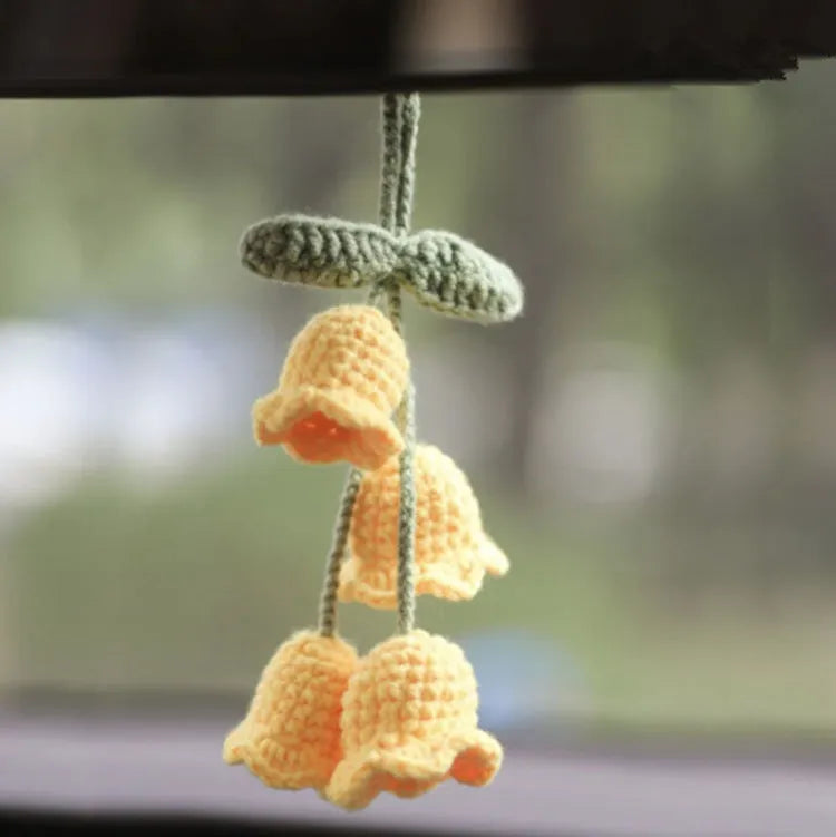 Green and white knitted wool car plant ornament with basin base and hanging rope.
