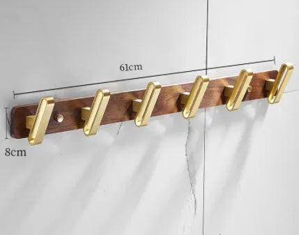 A row of black walnut bathroom clothes hooks with brushed brass metal details on a perforated mounting strip.