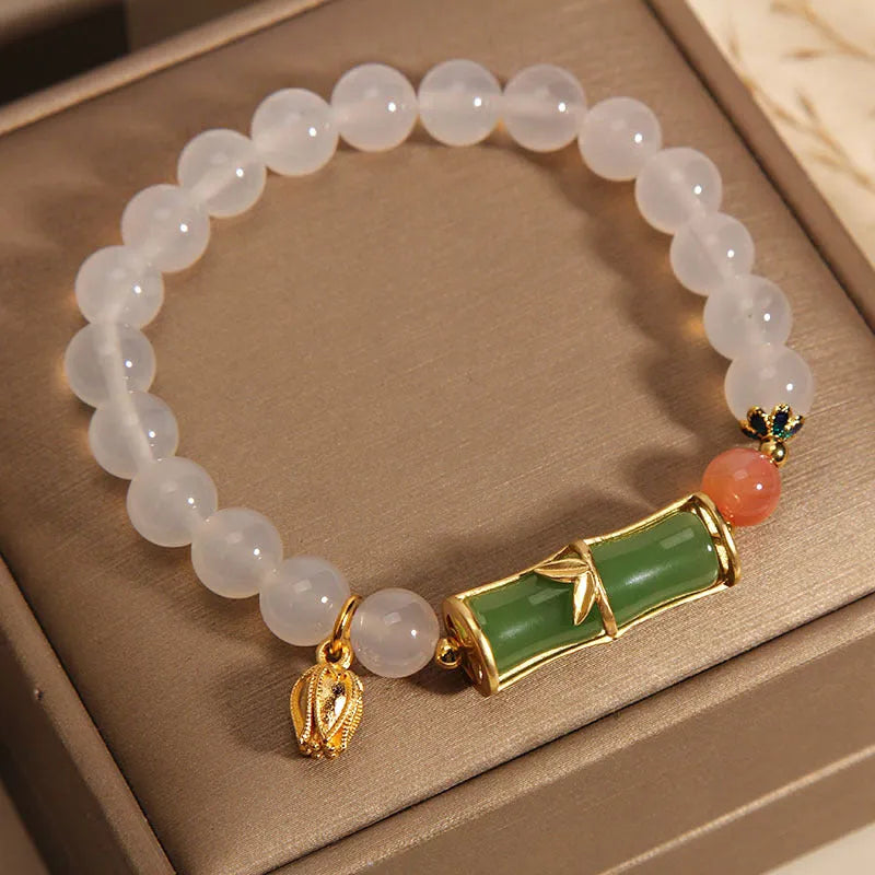 A women's bracelet with a textured jade bamboo bead and a white agate charm on a beaded string.