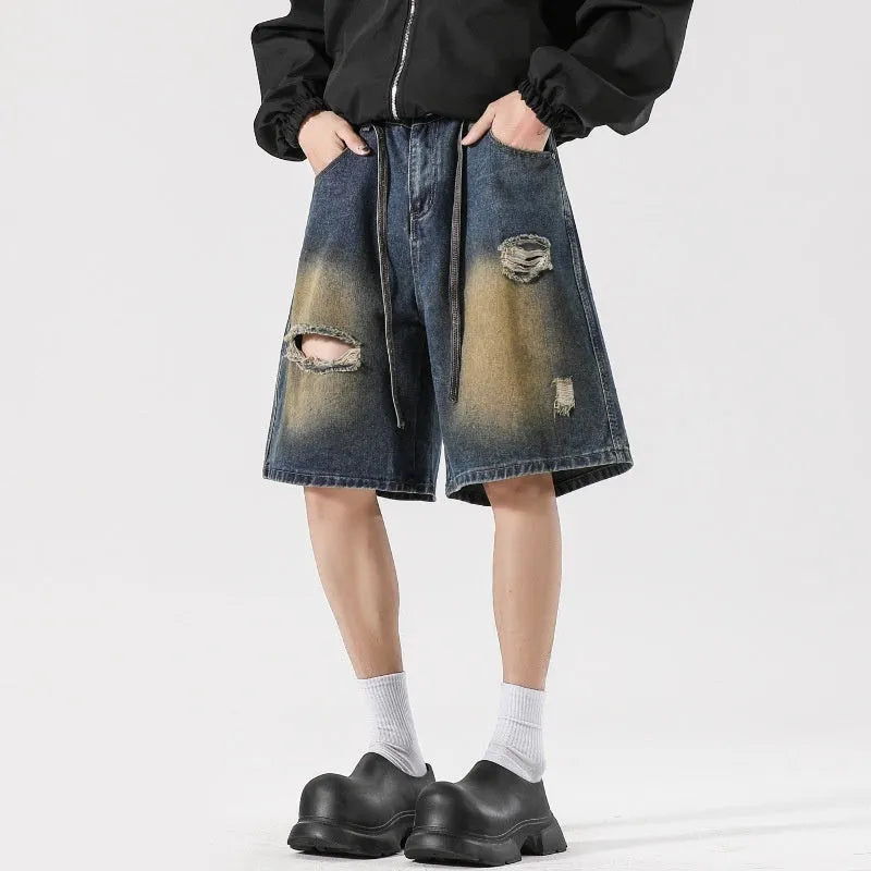 Man wearing loose fit retro blue ripped jeans with distressed details on knees and thighs