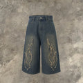 Men's black cropped denim shorts with a flame embroidery patch on the leg, showing straight cut.