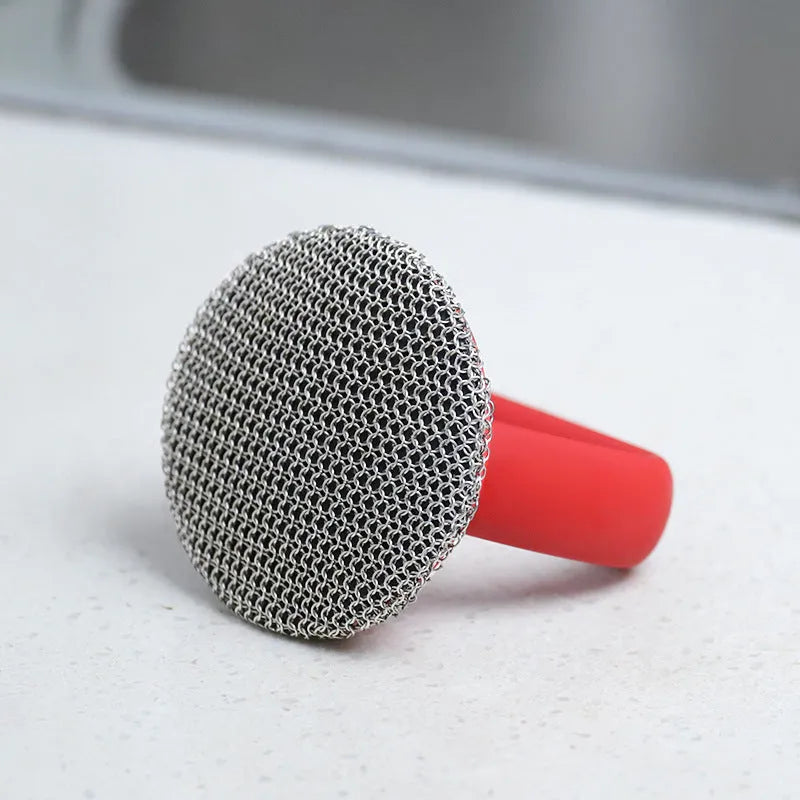 Round 316 stainless steel chainmail scrubber with red silicone handle on cast iron skillet