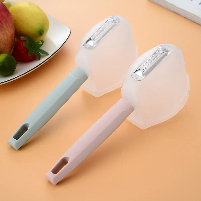 Stainless steel handle fruit peeler in pink colour with PP plastic body on a wooden surface