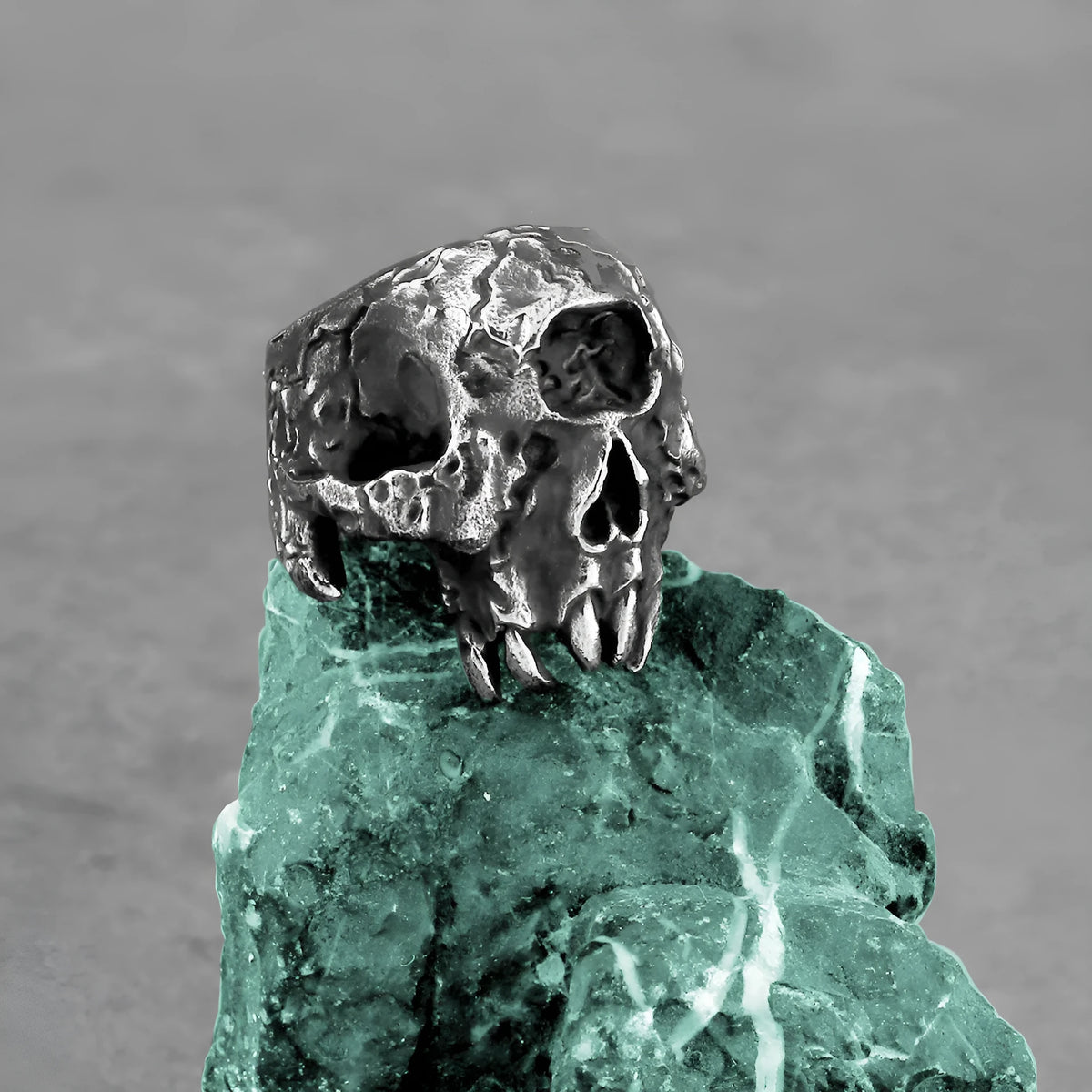 Silver tone alloy ring featuring a detailed one-eyed skull design on a black background.