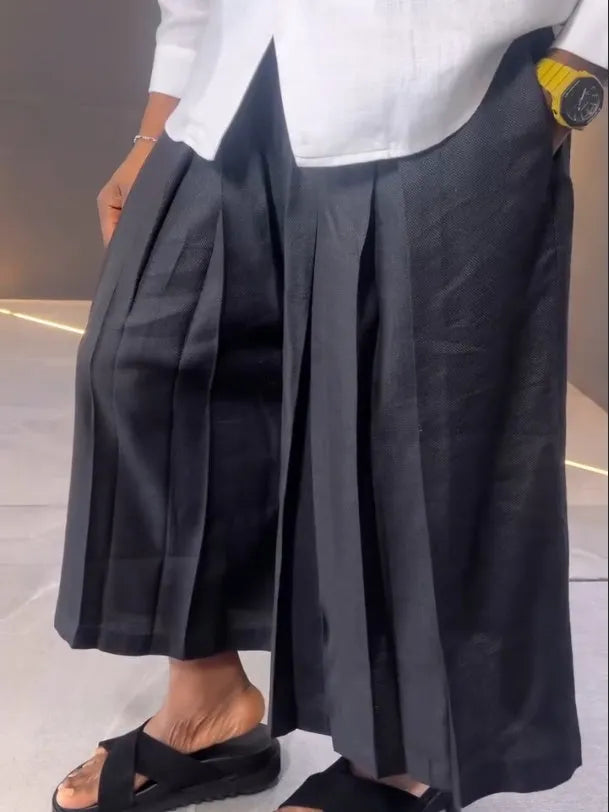 White asymmetric long sleeve shirt and black pleated trousers co-ord set on a hanger