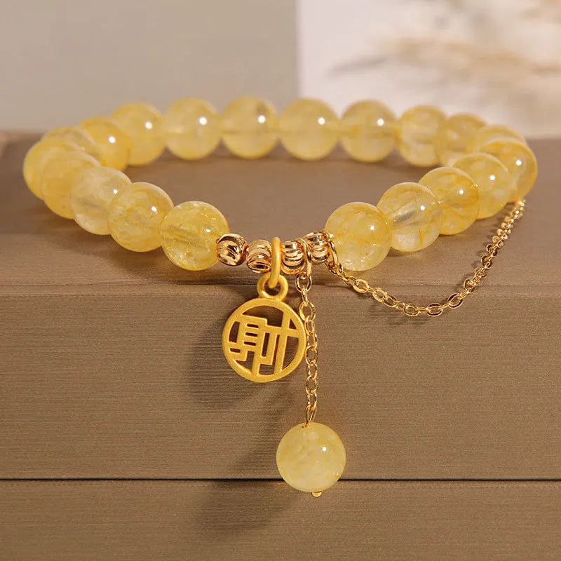 Women's natural citrine bracelet with gold electroplated Chinese character charm on an adjustable dark cord.