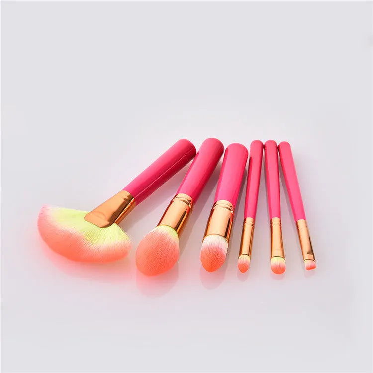 Pink cosmetic makeup brush set with wooden handles and synthetic nylon bristles on a flat surface