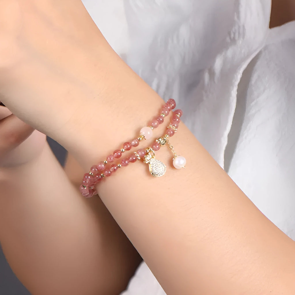 Women's geometric strawberry quartz crystal wallet bracelet on a wrist.