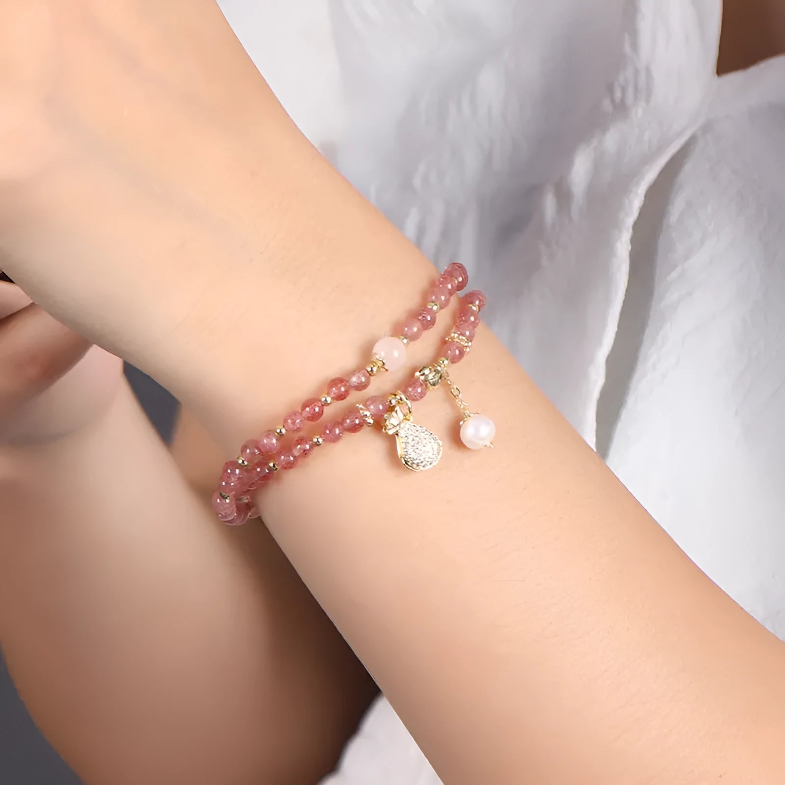Women's geometric strawberry quartz crystal wallet bracelet on a wrist.