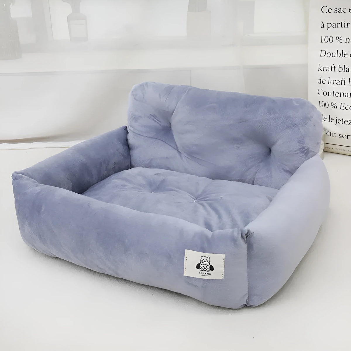 Blue plaid portable dog car bed nest with raised sides, shown on a vehicle seat.