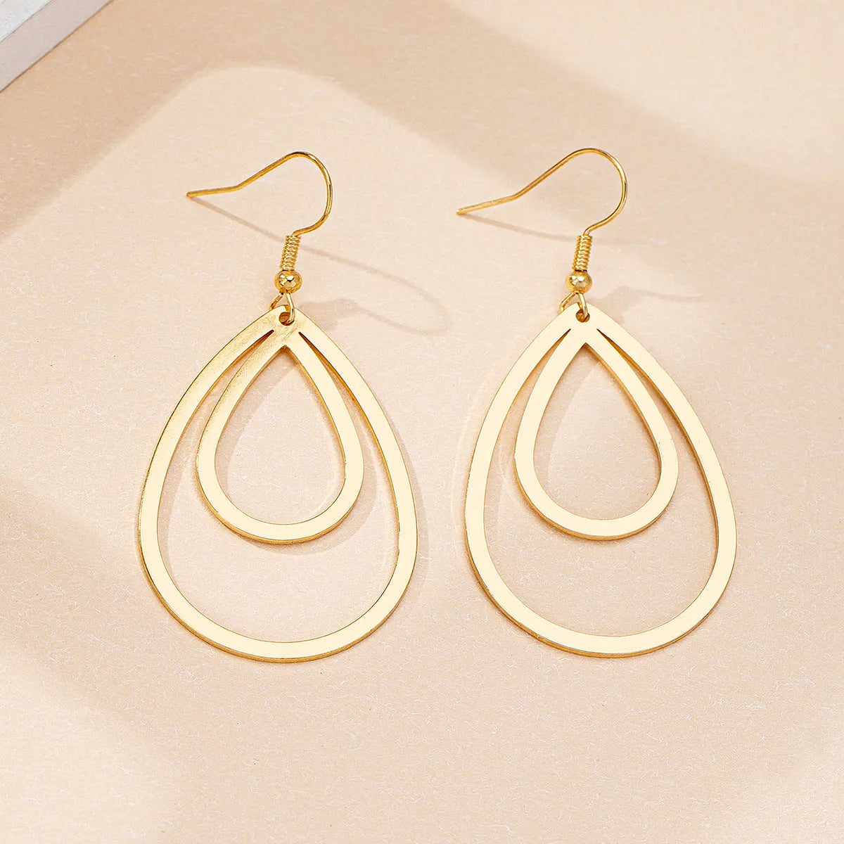 Golden yellow hollow drop earrings made from iron, shown as a pair with an open drop shape