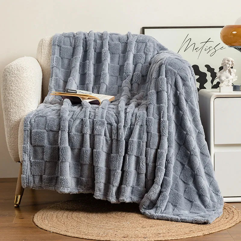 Geometric pattern polyester velvet blanket in dark grey, shown draped over a sofa.