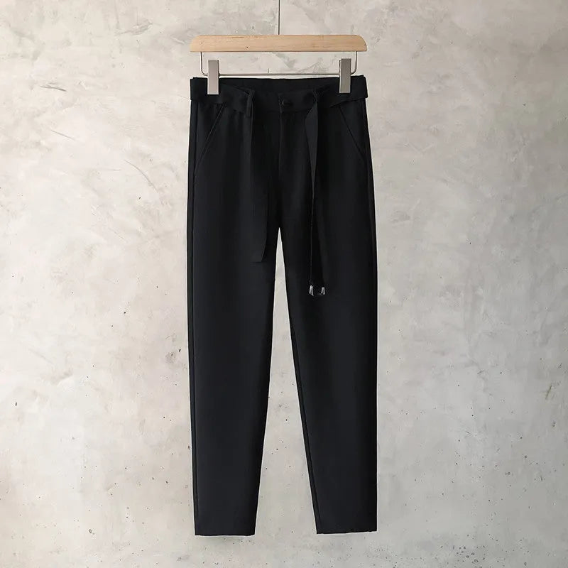 Boy wearing slim straight tapered wool trousers in a grey colour, showing the straight leg opening and belt loops.