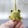 Handmade woven plush frog car pendant in green hanging from rear-view mirror