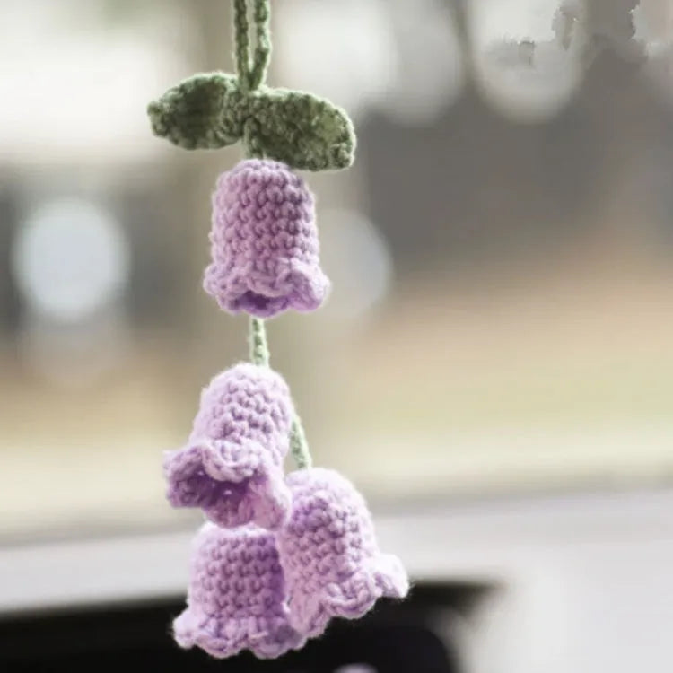 Green and white knitted wool car plant ornament with basin base and hanging rope.