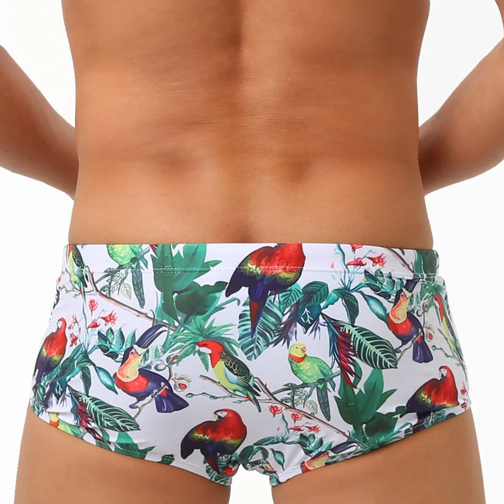 Men's blue swimming trunks with a colourful flowers and birds print, showing the boxer style and cup cover.