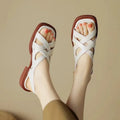 Women's glossy patent leather square toe sandals with winding tape fastening on a neutral background.