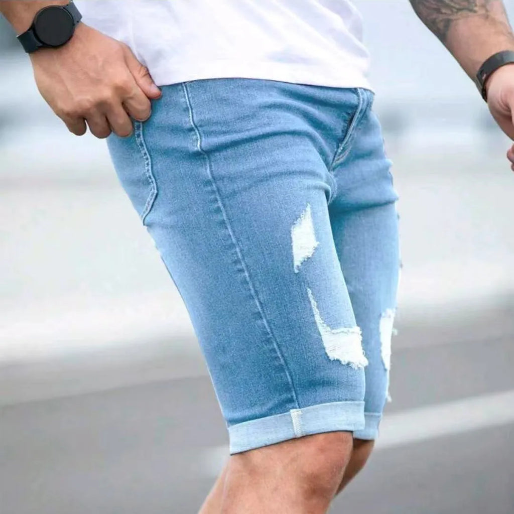 Men's sky blue denim shorts with distressed multi-hole design and straight leg cut