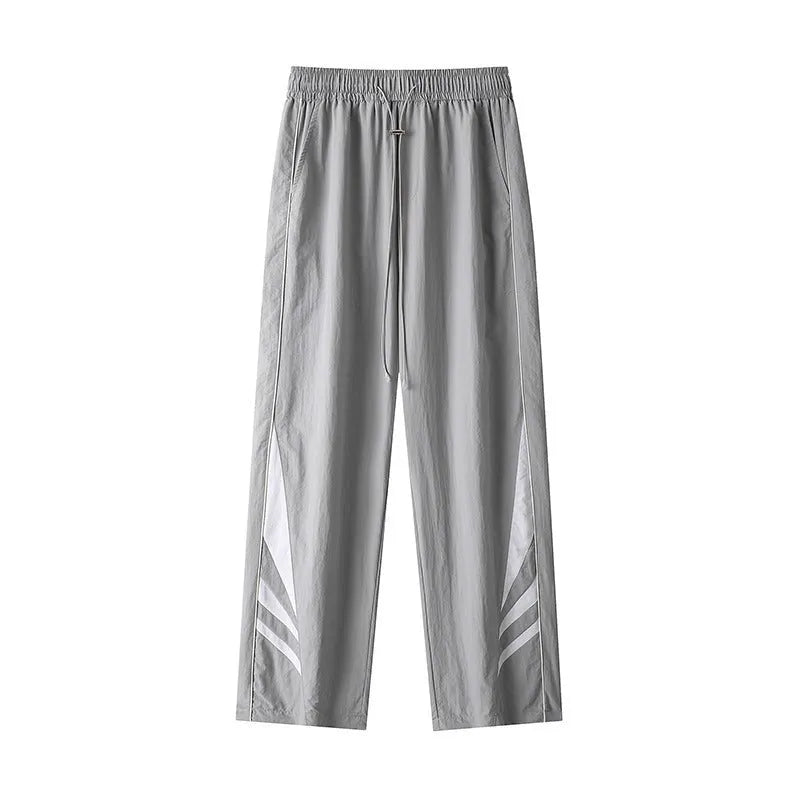 Man wearing grey straight-leg casual trousers with a button fly and elasticated waist.