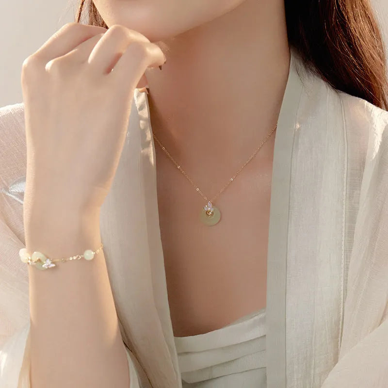 Silver necklace with orchid flower and peace buckle pendant on an O-ring chain, featuring a safety clasp.