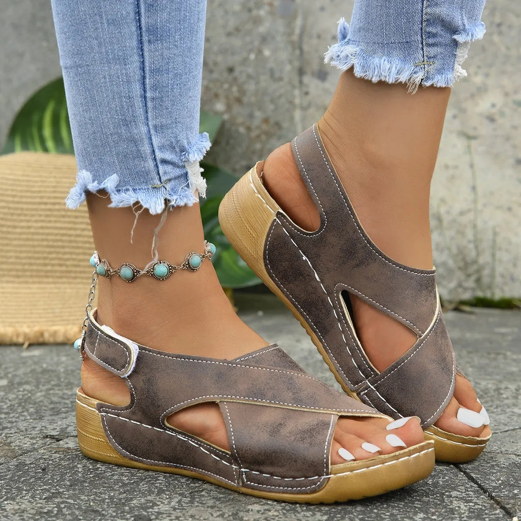 Women's brown Roman sandals with a platform sole, skirt trim detail, and Velcro strap fastening.