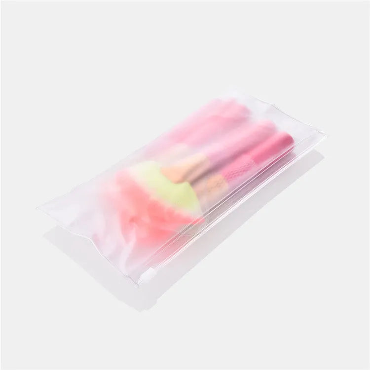 Pink cosmetic makeup brush set with wooden handles and synthetic nylon bristles on a flat surface