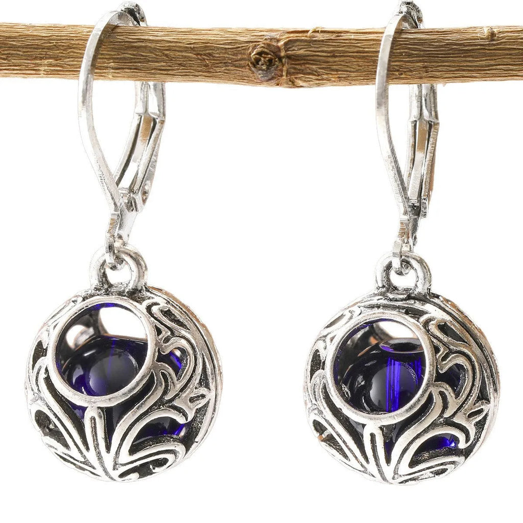 Silver geometric hollow pendant earrings with vintage engraving and a central blue gemstone on a zinc alloy setting.