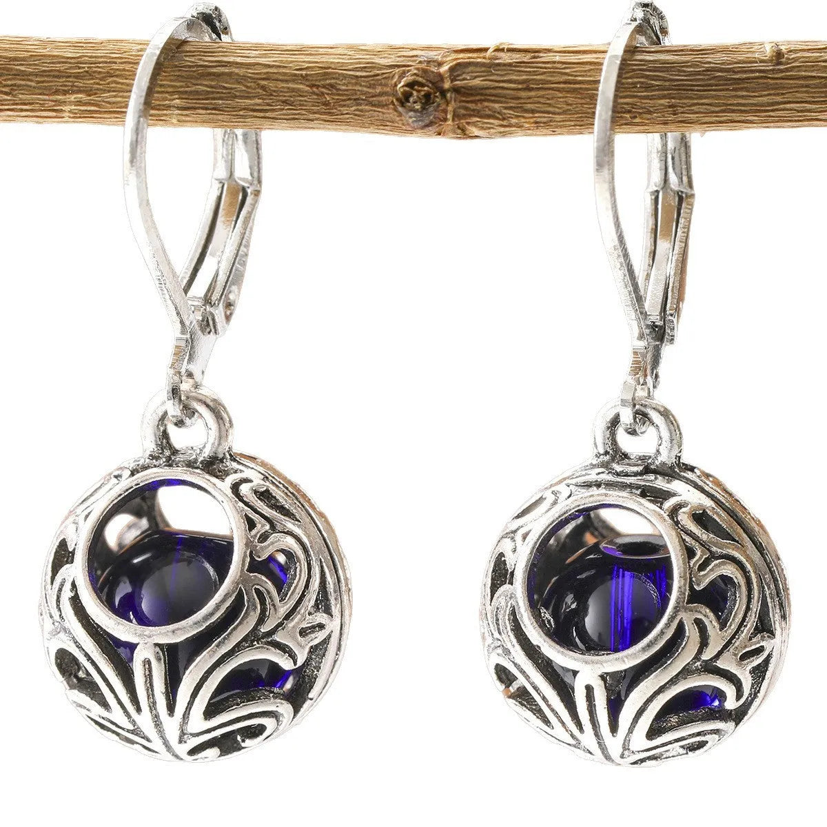 Silver geometric hollow pendant earrings with vintage engraving and a central blue gemstone on a zinc alloy setting.
