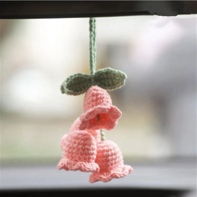 Green and white knitted wool car plant ornament with basin base and hanging rope.