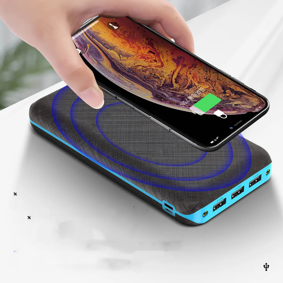Black portable power bank with wireless Qi charging pad, three USB ports, and LED flashlight for iPhone Samsung Xiaomi phones