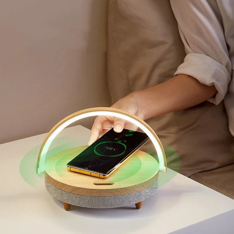 Marble pattern wireless charging LED night light with Bluetooth speaker and phone holder on a wooden nightstand.