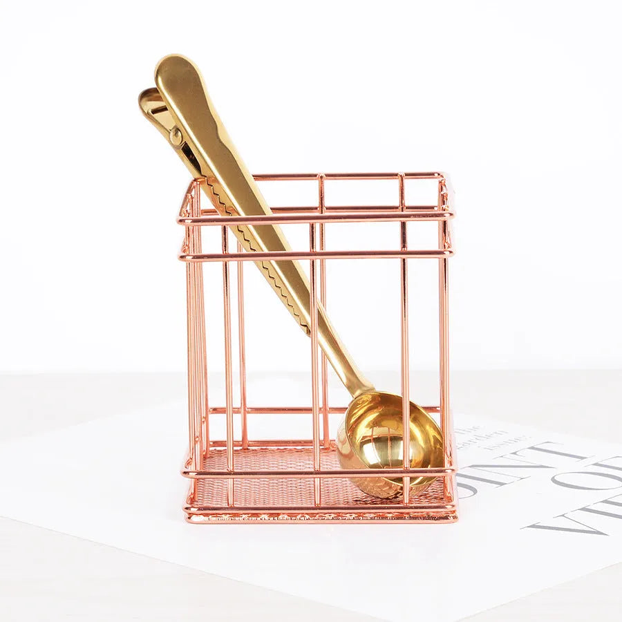Rose gold iron wire square pen holder on desk holding pens and a ruler