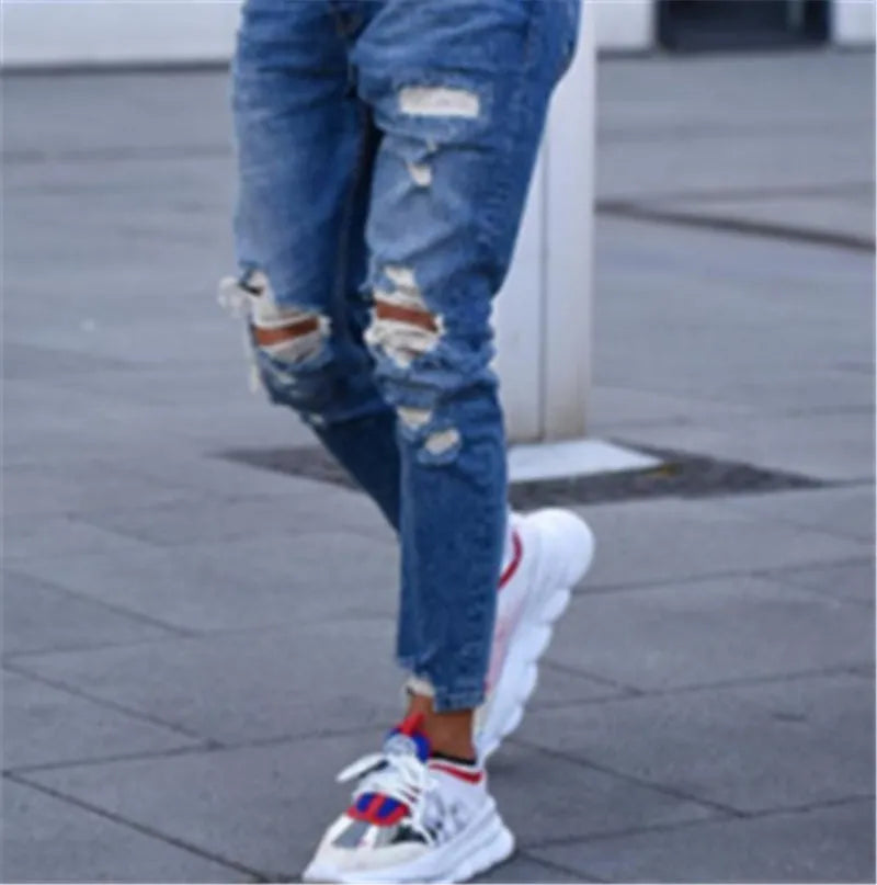 Deep blue men's jeans with distressed hole details and five pockets laid flat.