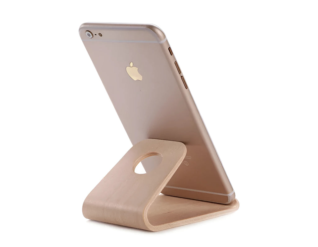 Solid walnut wooden stand holding an iPhone with charging cable routed through integrated channel
