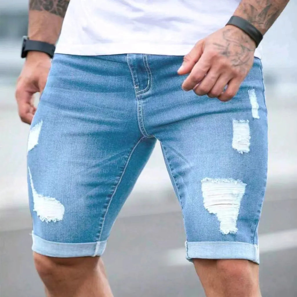 Men's sky blue denim shorts with distressed multi-hole design and straight leg cut