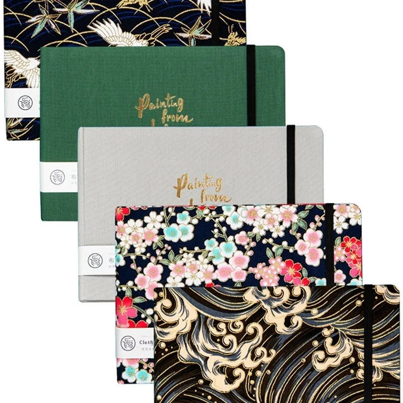 Feiluniao handmade fabric watercolour notebook open on a table with paintbrush.