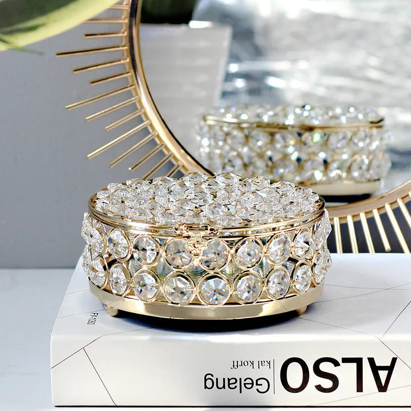 Transparent crystal glass jewelry storage box with ornate French gold metal frame.