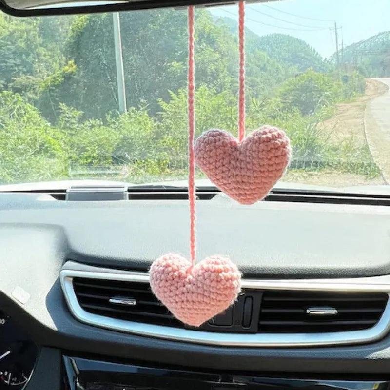 Green and white knitted wool car plant ornament with basin base and hanging rope.