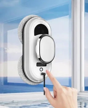 White automatic high altitude window cleaning machine with remote control and cleaning accessories on a surface.