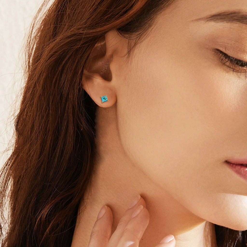 Gold-plated drop earrings with pear-shaped candy-coloured zircon stones on a white background.