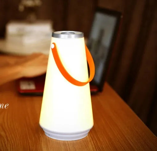 White rechargeable LED bedside night light with touch control on a wooden table.