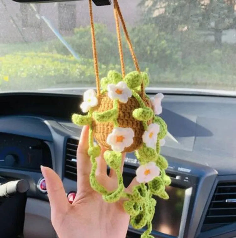 Green and white knitted wool car plant ornament with basin base and hanging rope.