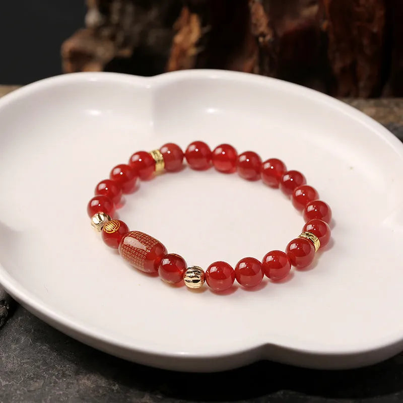 Close-up of a red agate Guanyin bracelet with detailed rosary bead edging on a wrist.