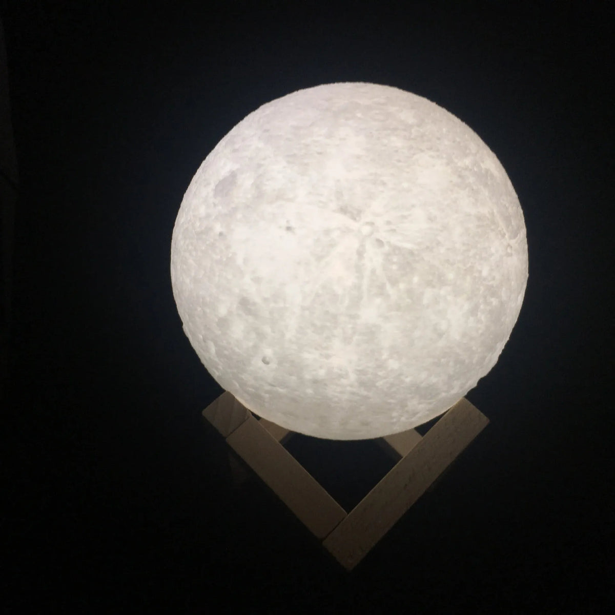 3D printed white moon lamp on a wooden stand with touch-control ring at base